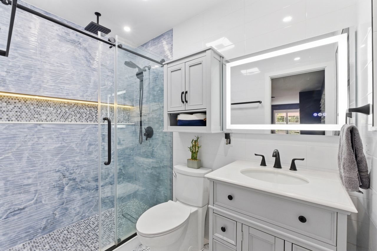 Renovated bathroom with blue marble tile, glass shower, and modern fixtures