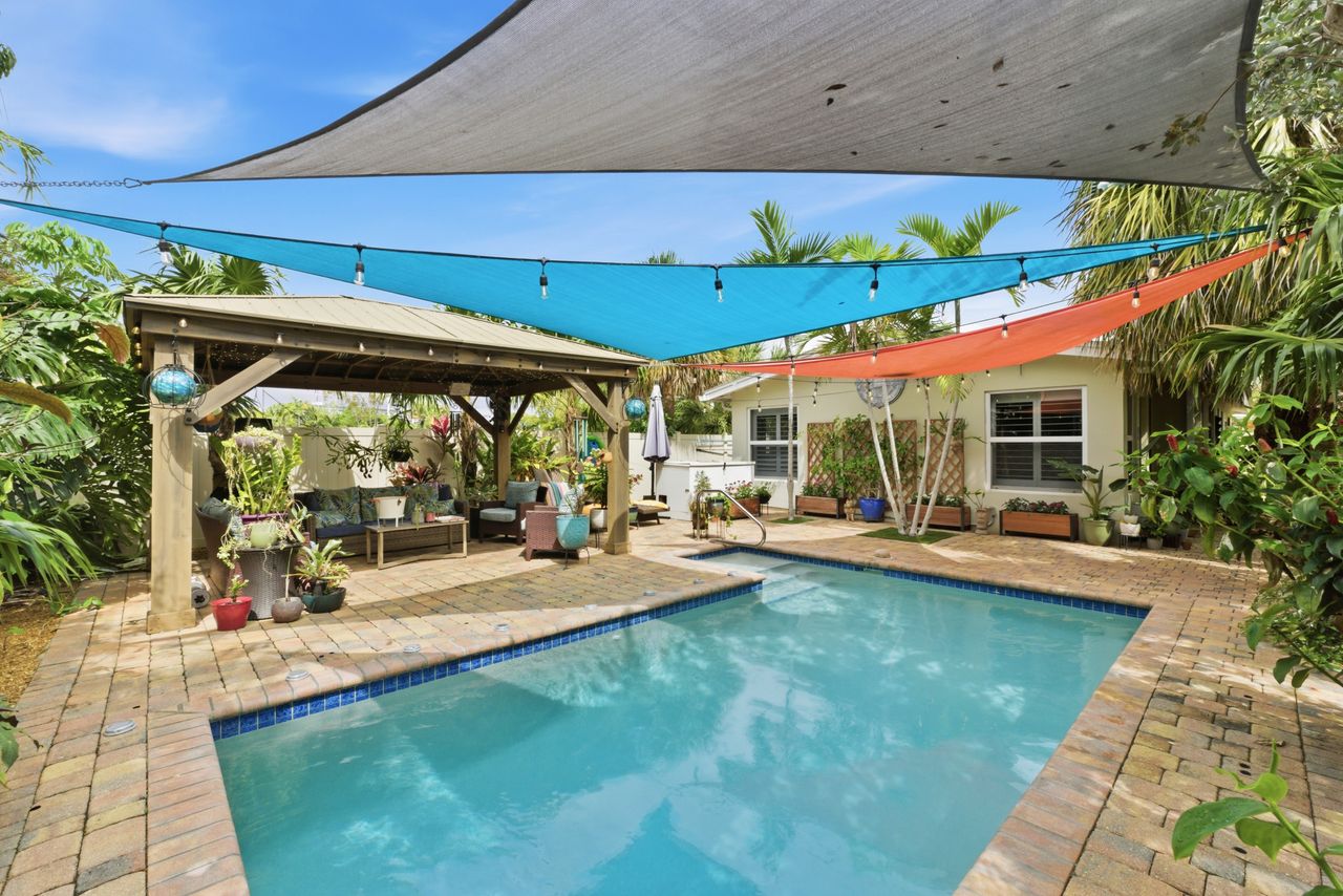 Private pool with colorful shade sails and tropical landscaping